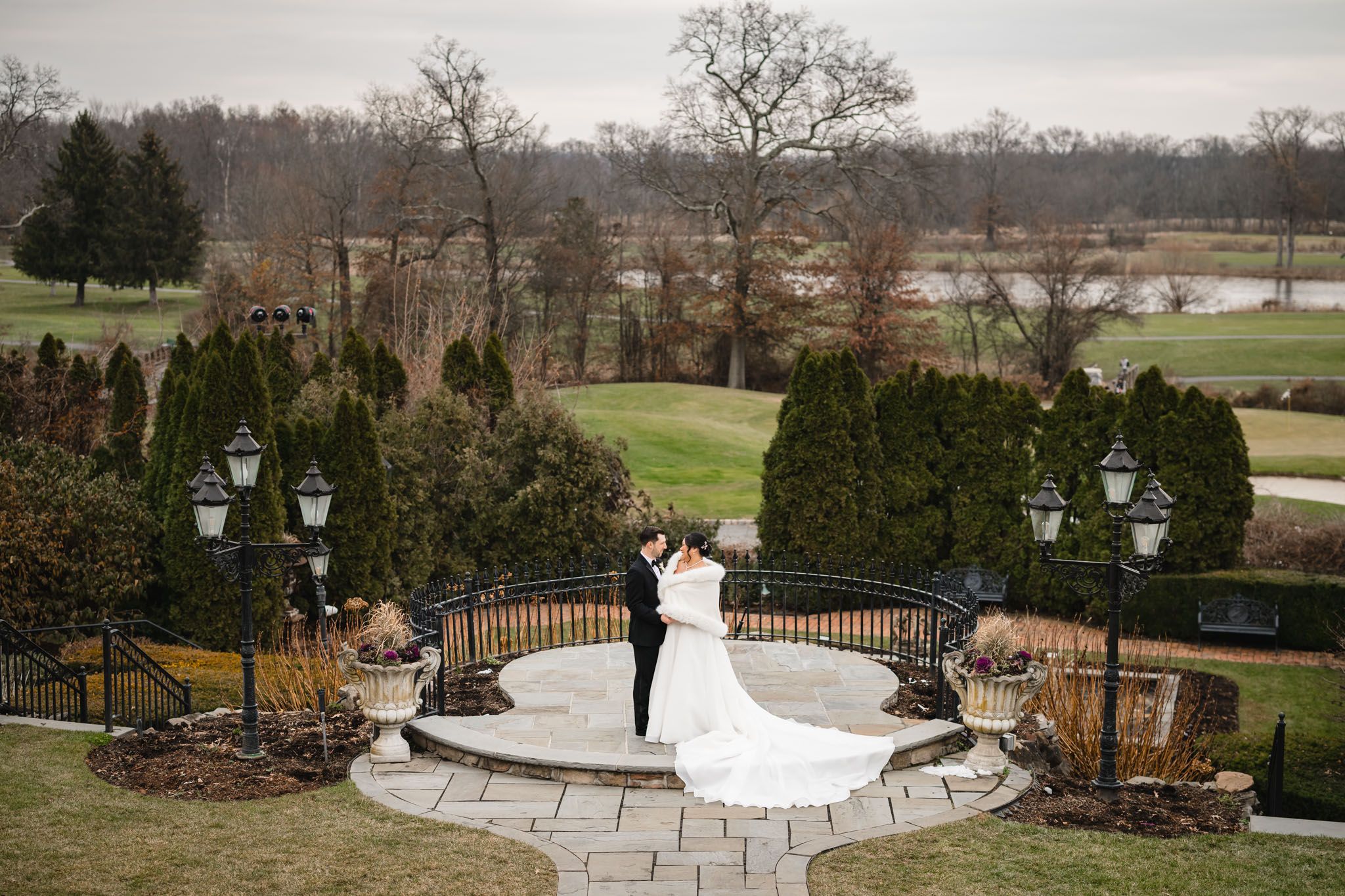 An aerial view of a wedding ceremony on a circular stone terrace surrounded by winter landscaping.
