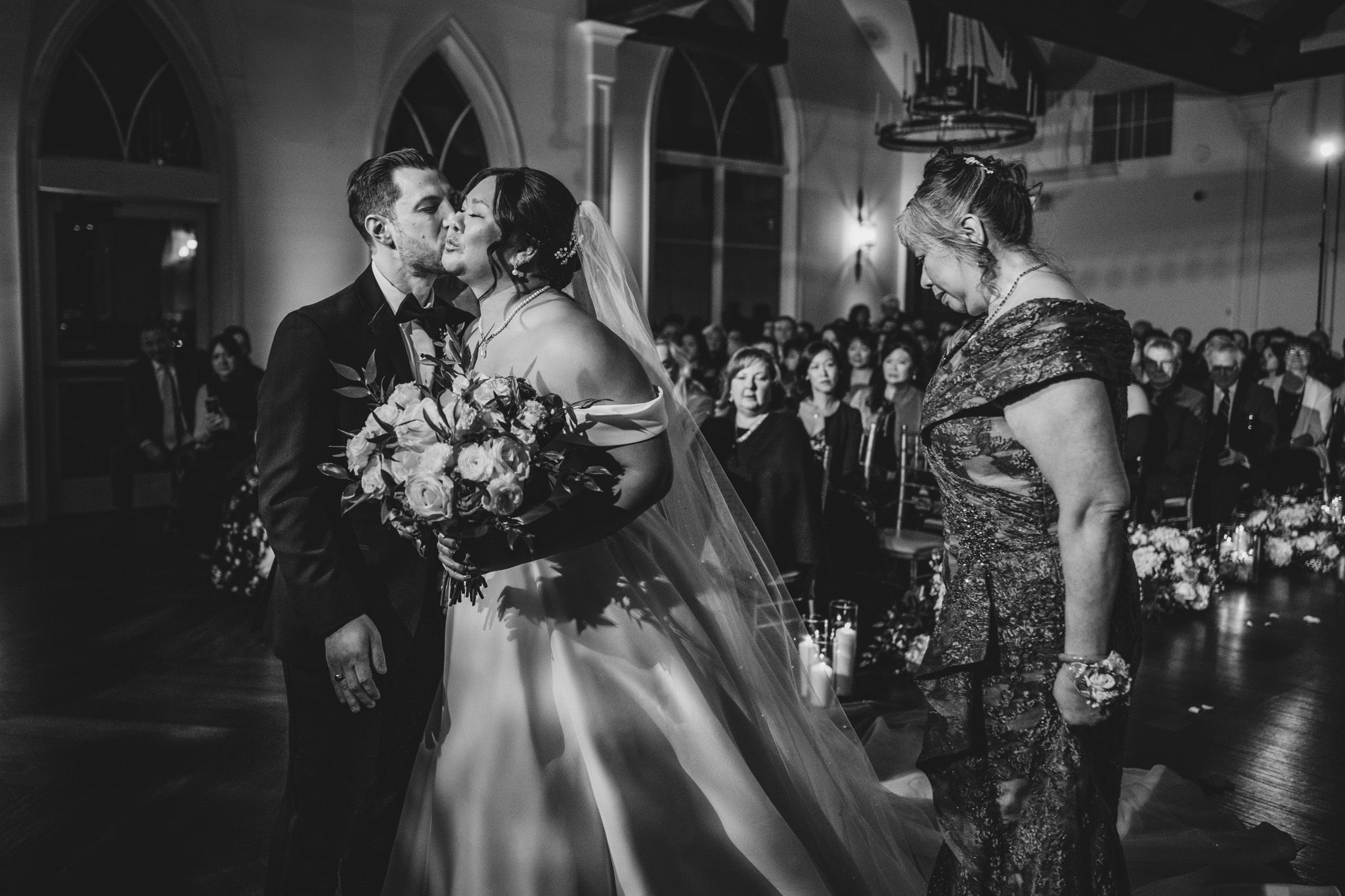 Black and white capture of intimate wedding ceremony moment in church setting.