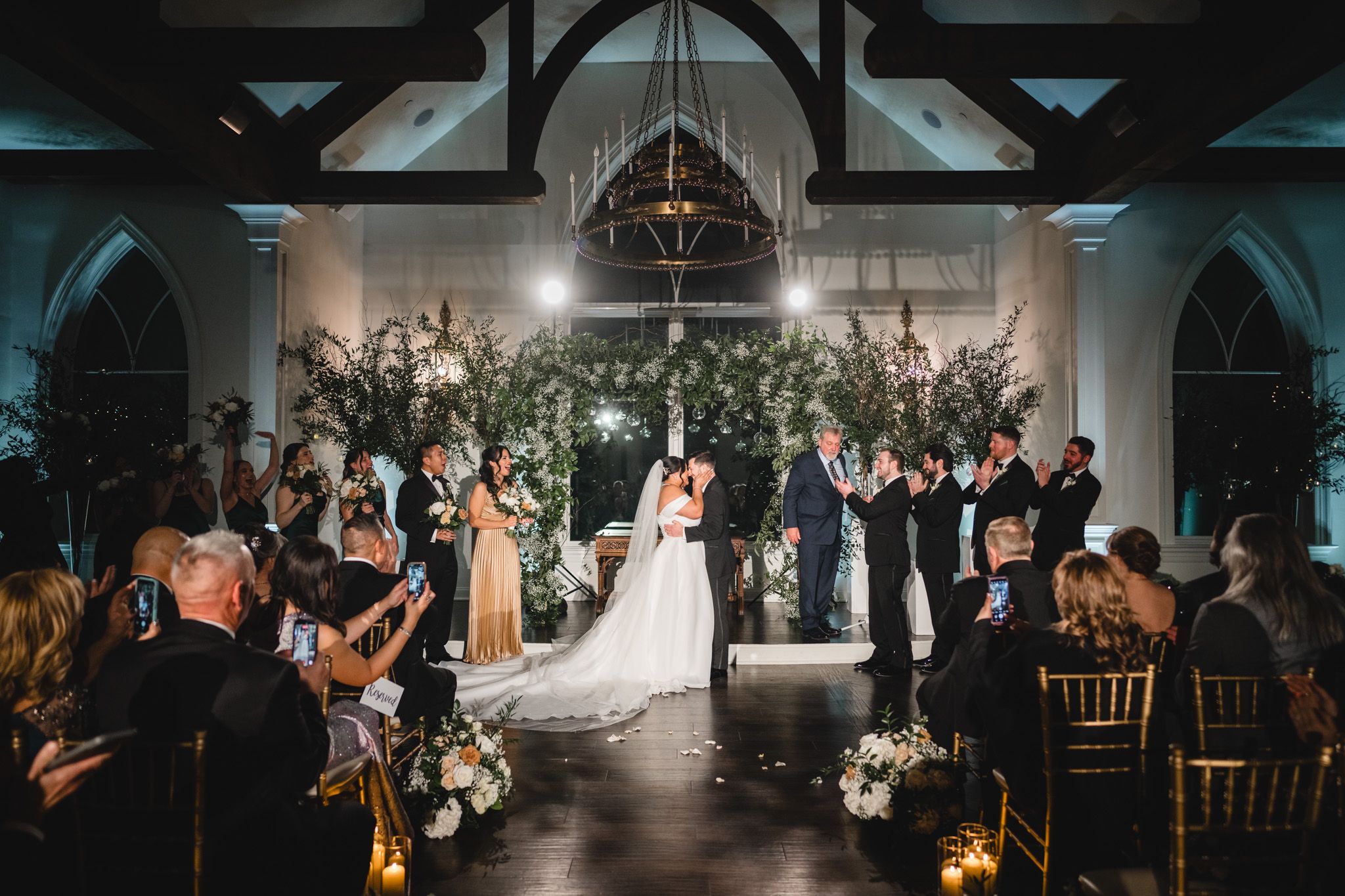 Wedding ceremony in modern church with floral arch and elegant guest seating.