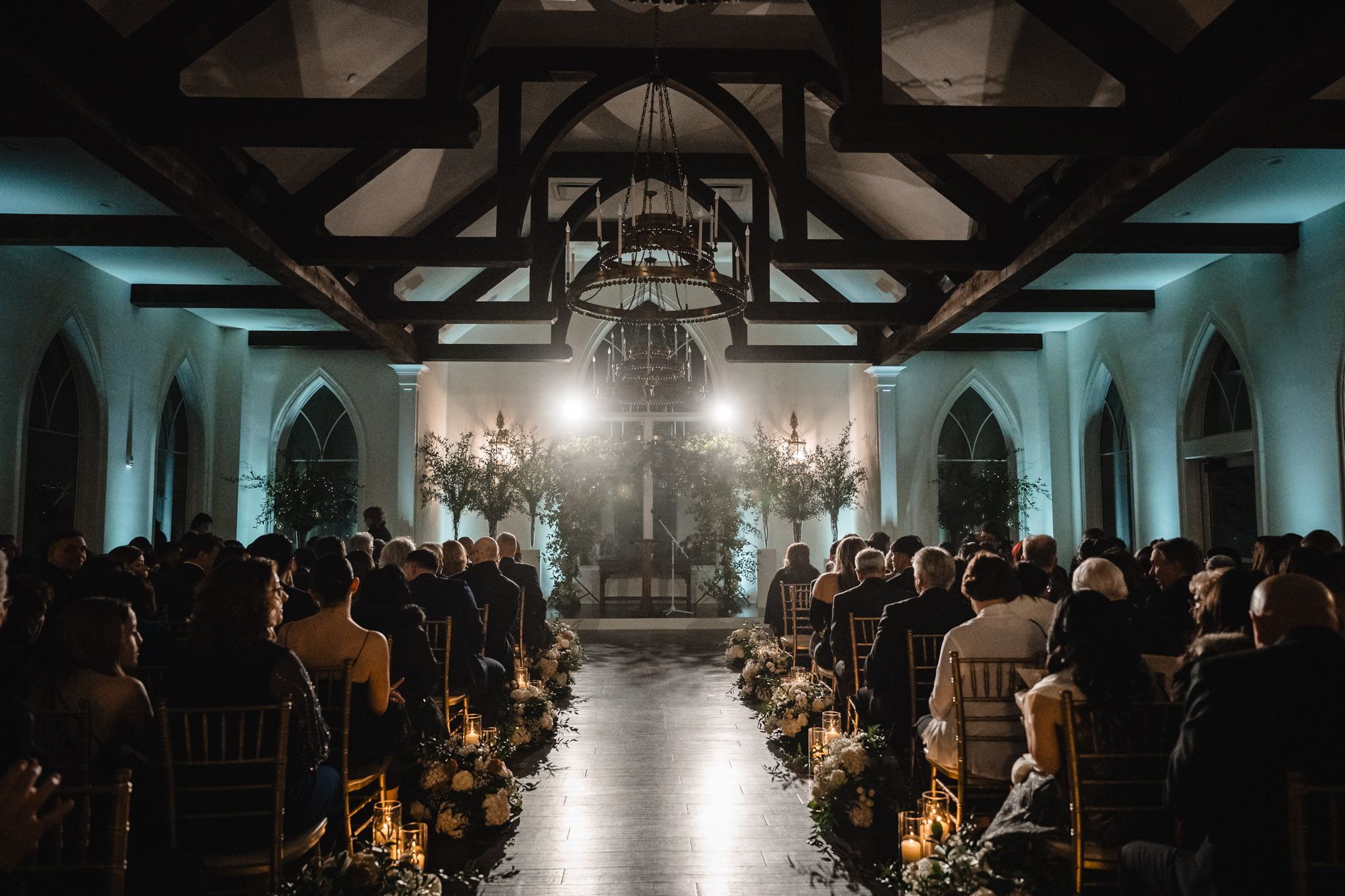 Atmospheric indoor wedding ceremony with exposed wooden beams and dramatic lighting.