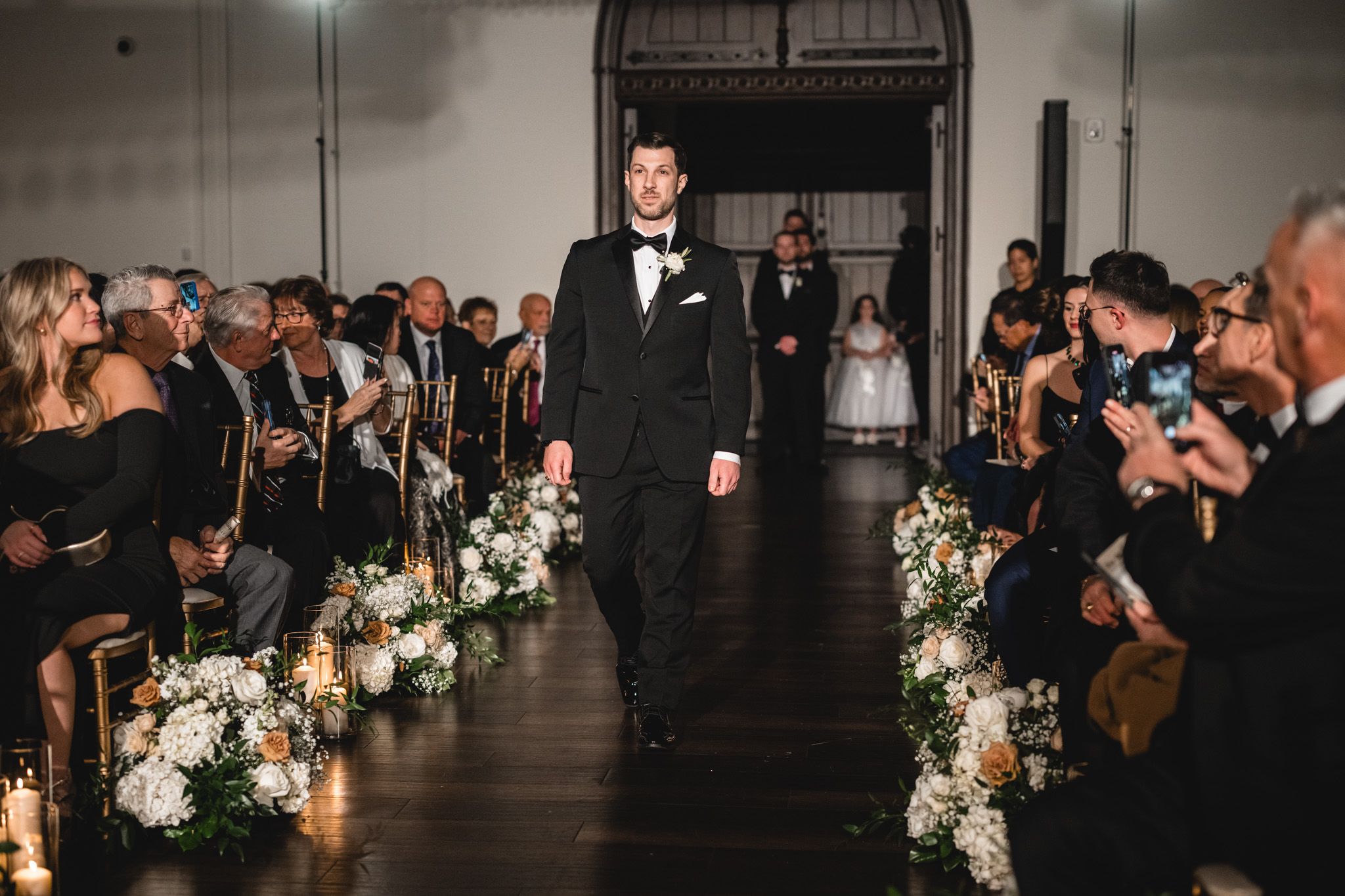 Wedding ceremony aisle decorated with romantic floral arrangements and candlelight.