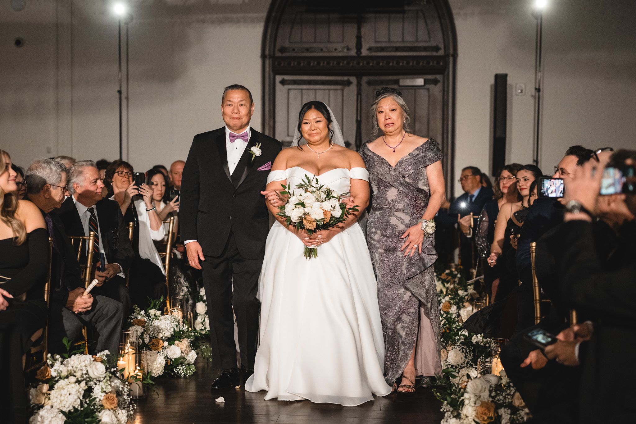 Wedding processional down aisle with elegant floral arrangements lining the path.