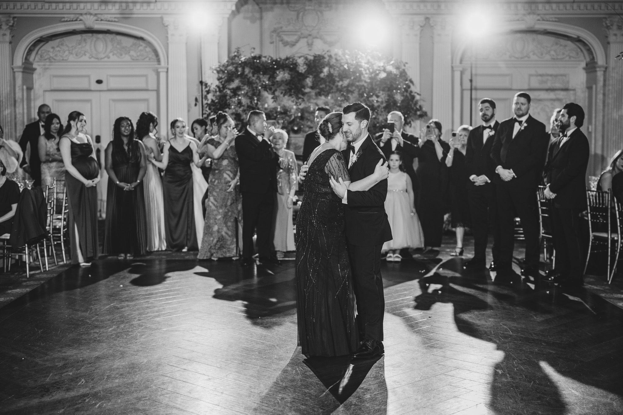 Intimate first dance moment captured in black and white during elegant ballroom reception.