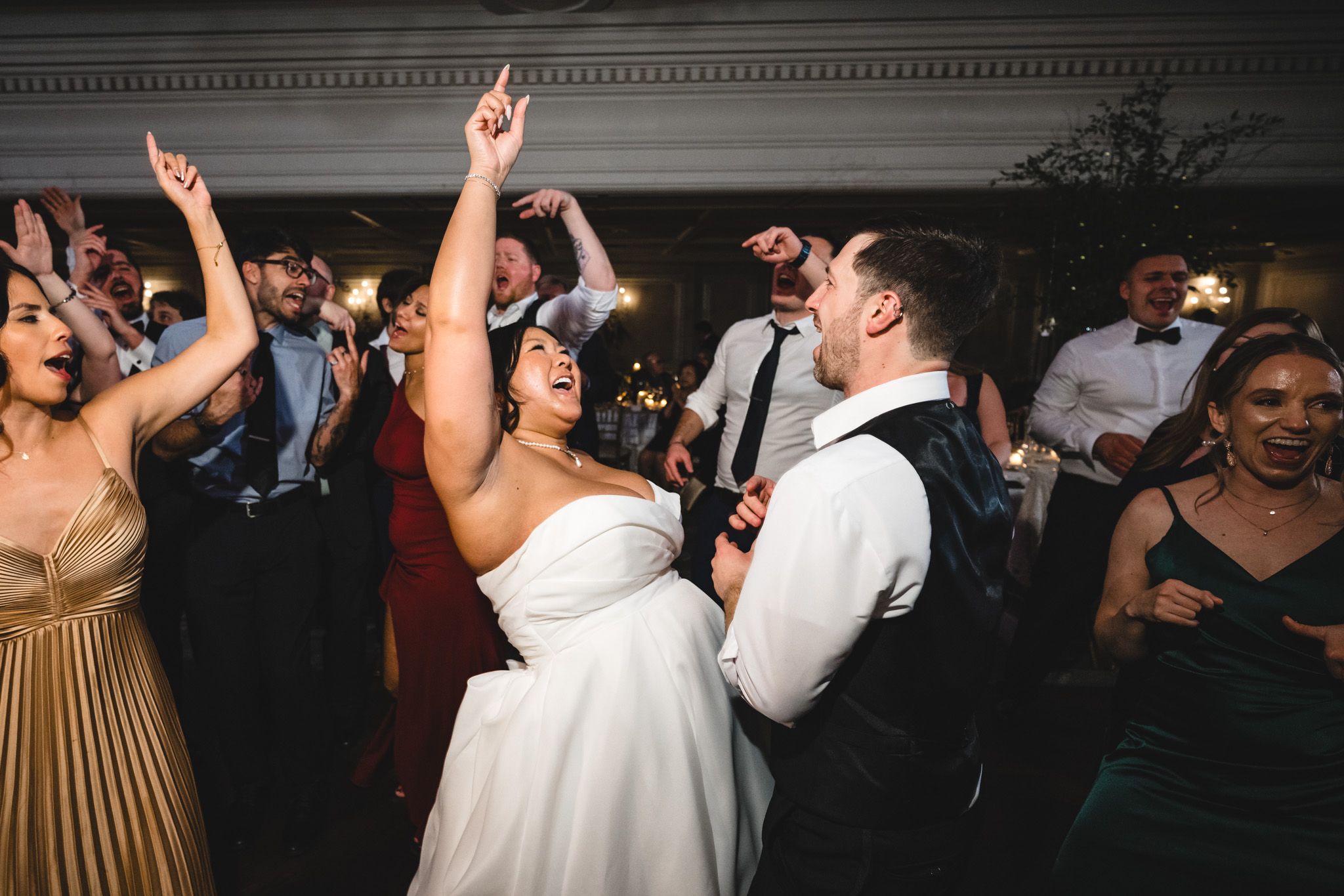 Energetic dancing and celebration at an elegant indoor wedding reception.