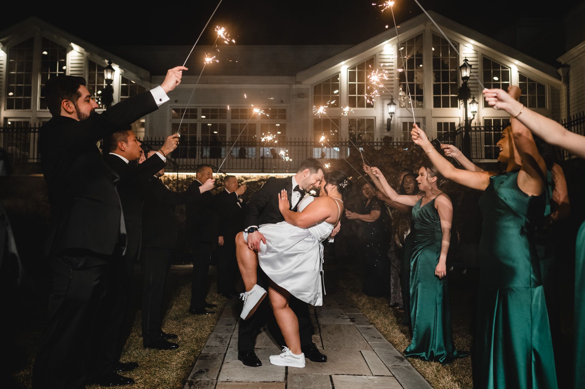 Wedding guests hold sparklers during an outdoor nighttime celebration.