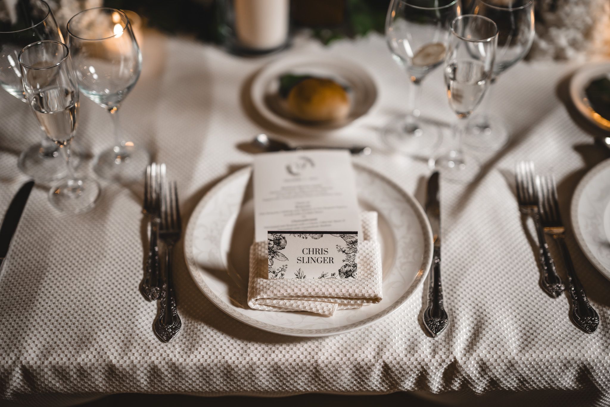 Formal place settings with white linens, crystal glassware and elegant dinnerware.