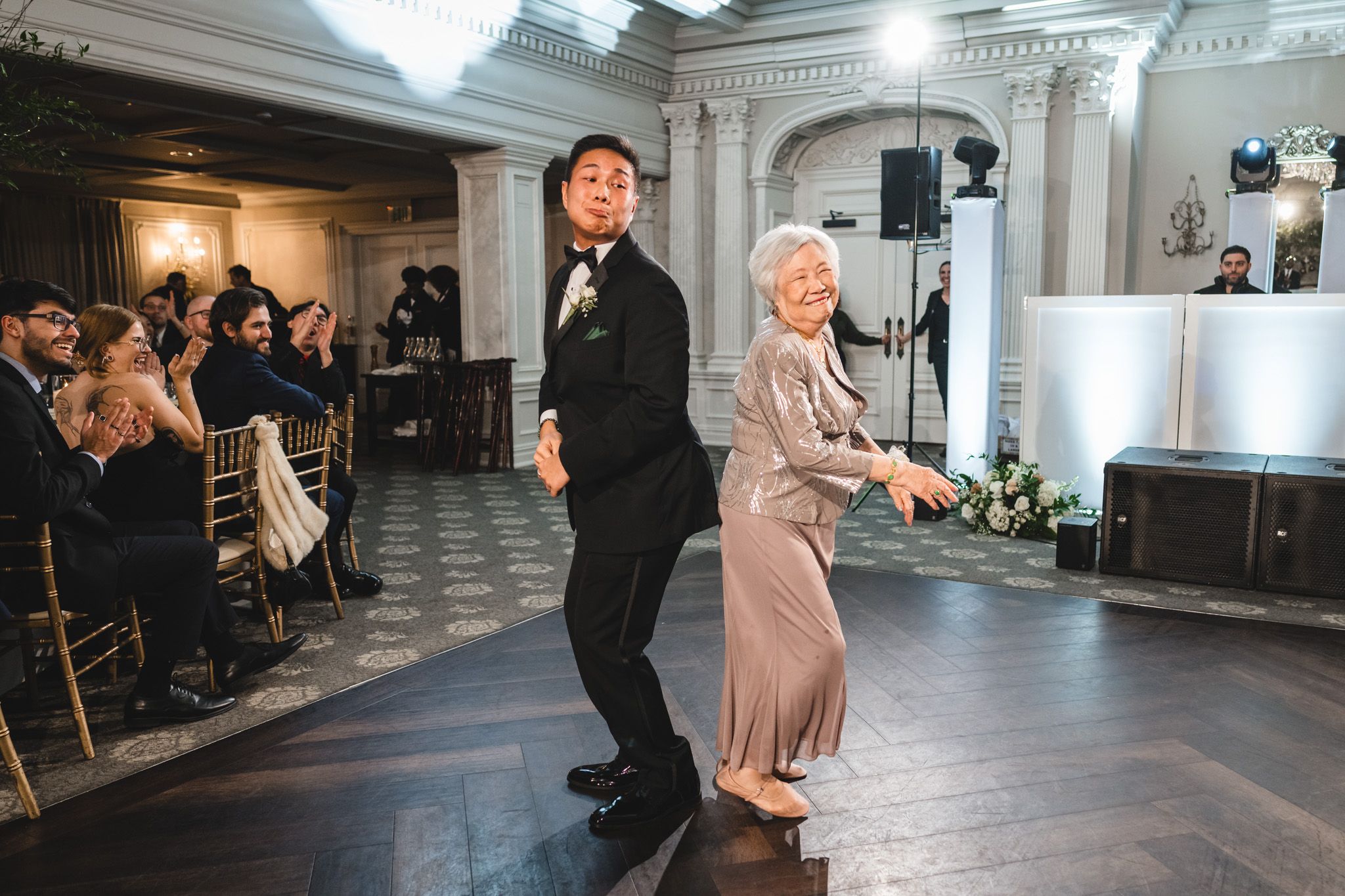 Wedding reception venue with guests mingling in an elegant white-columned ballroom.