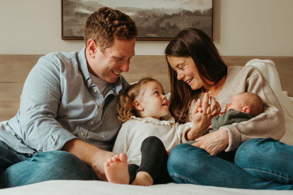 Intimate family moment on a cozy bed with newborn and toddler.