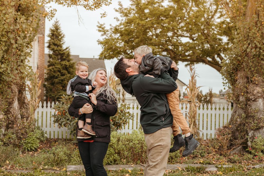 Happy family playing and laughing together in autumn garden with white picket fence.