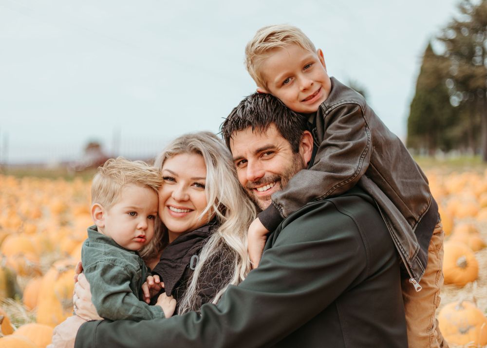 Close-knit family sharing warm embrace against autumn rural backdrop.