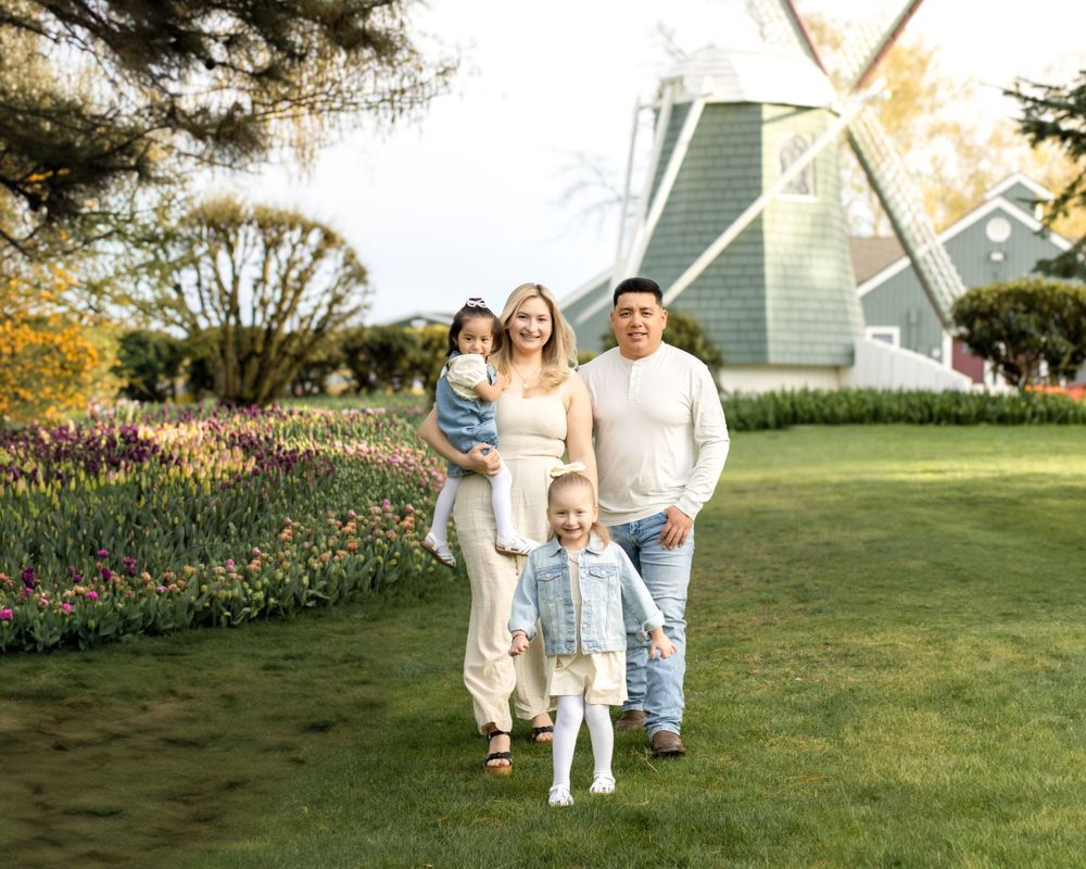 Family standing together in garden with windmill and spring flowers in background.