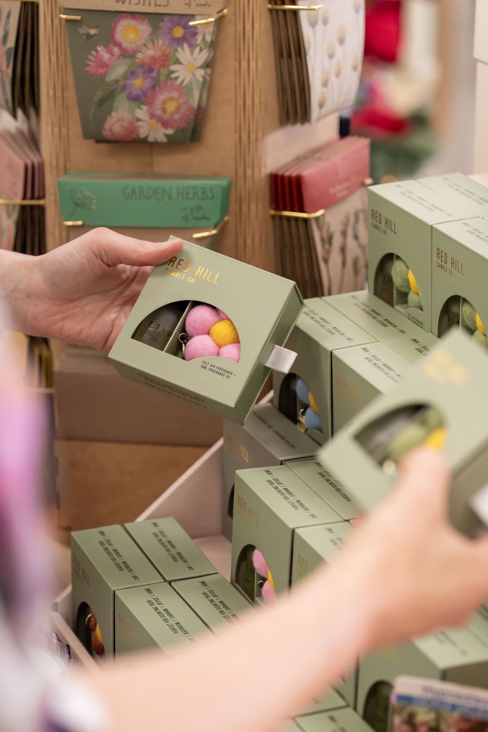 Green gift boxes being arranged in a retail display with pastel decorative elements.