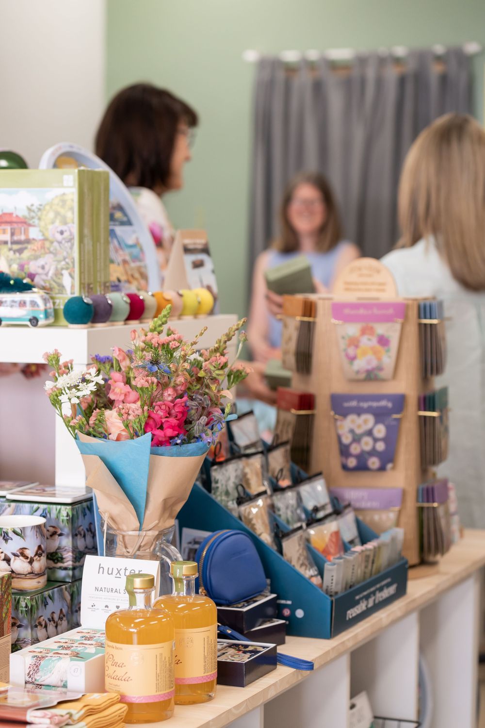 Retail display table with colorful floral arrangements and gift items arranged in a boutique setting.