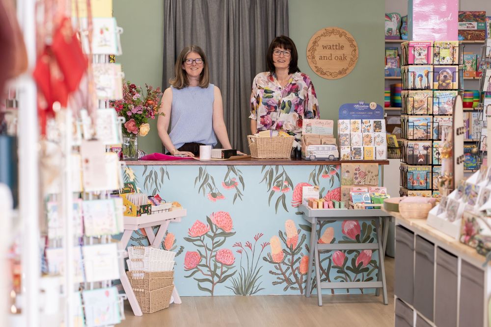 Colorful retail store interior with pink and green decor displaying beauty and lifestyle products on shelves.
