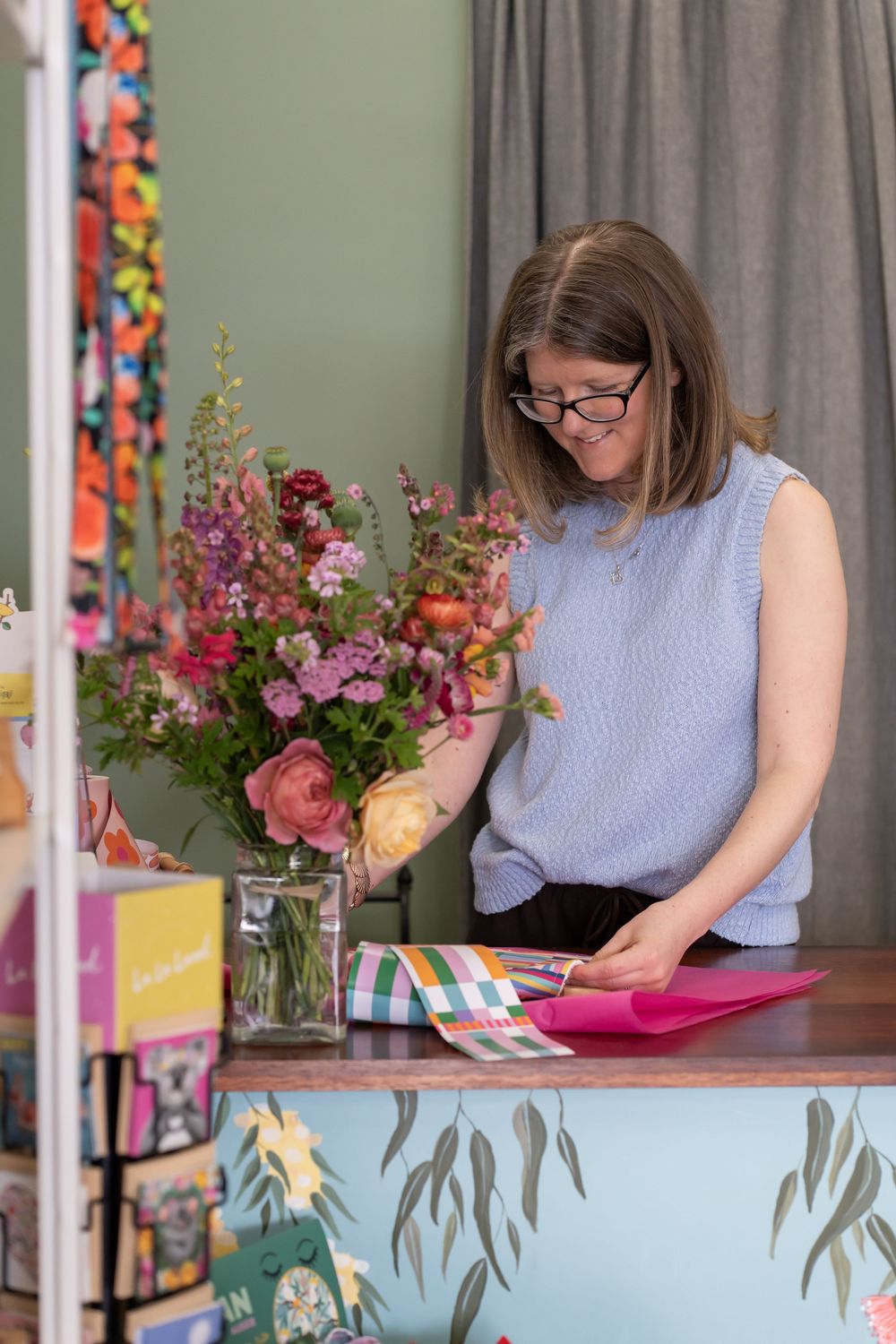 A creative workspace with colorful floral arrangements and design materials on a desk.