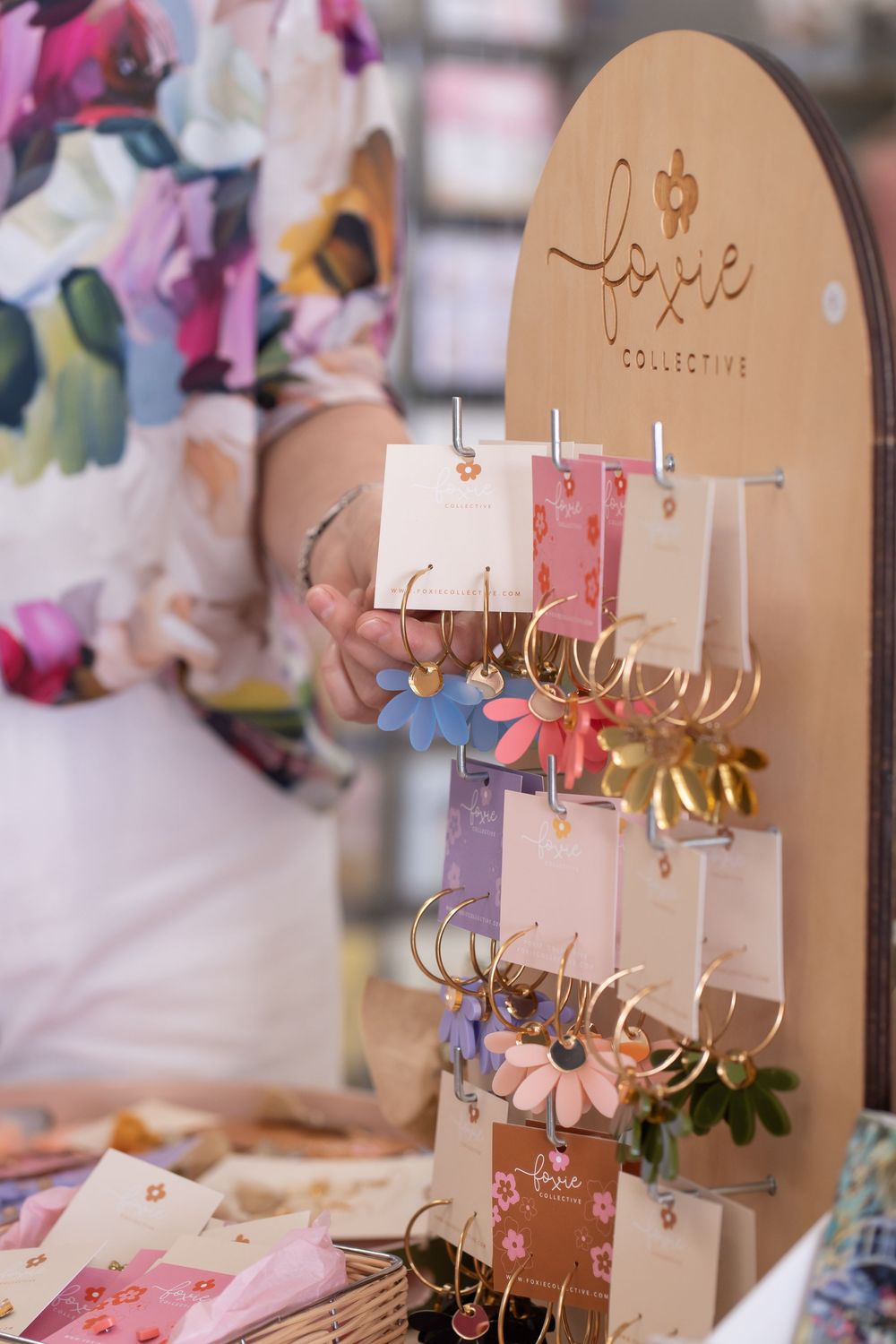 Pink and beige jewelry display stands with earrings arranged on hooks in a retail setting.