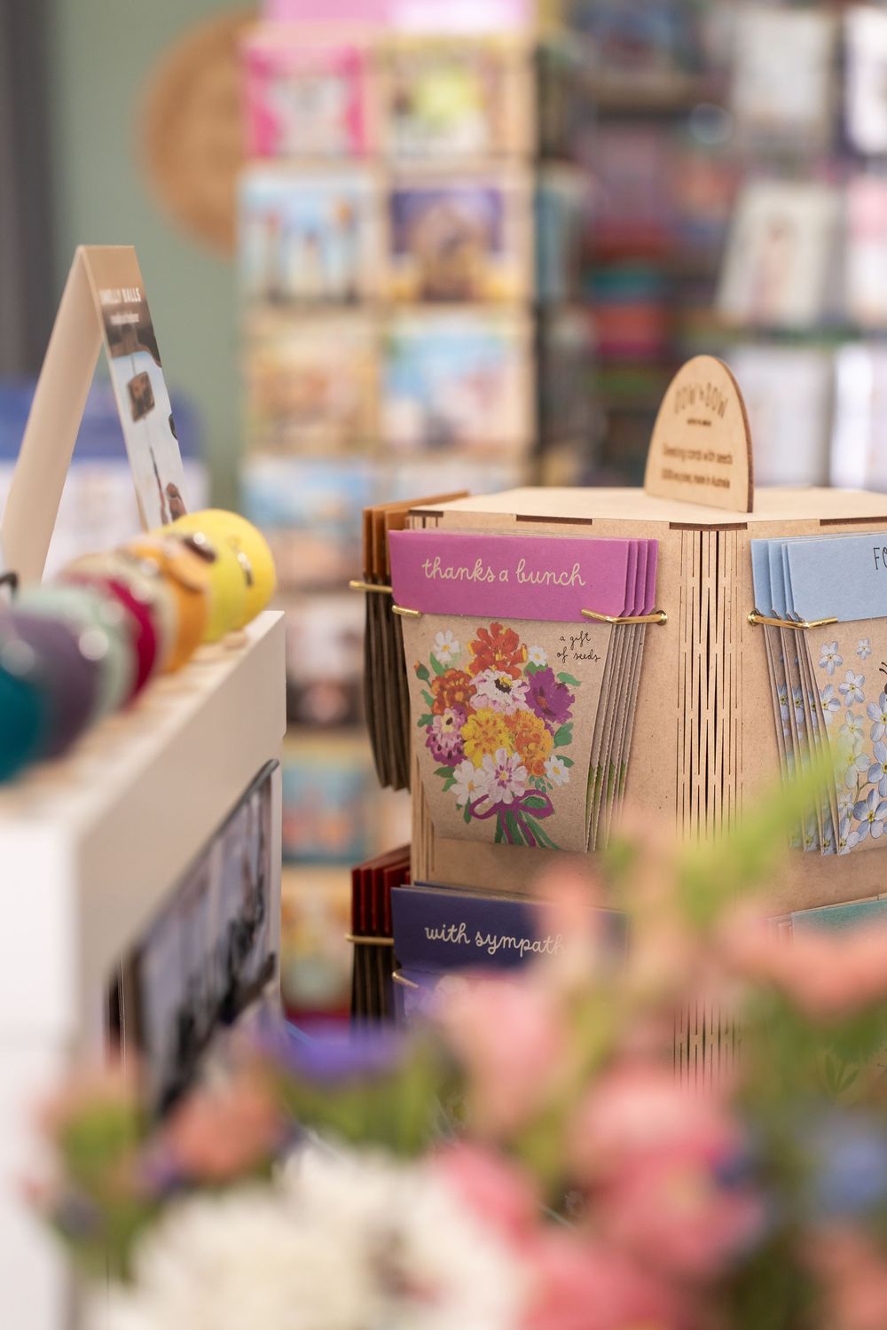 Colorful floral greeting cards displayed on wooden stands in a retail shop setting.