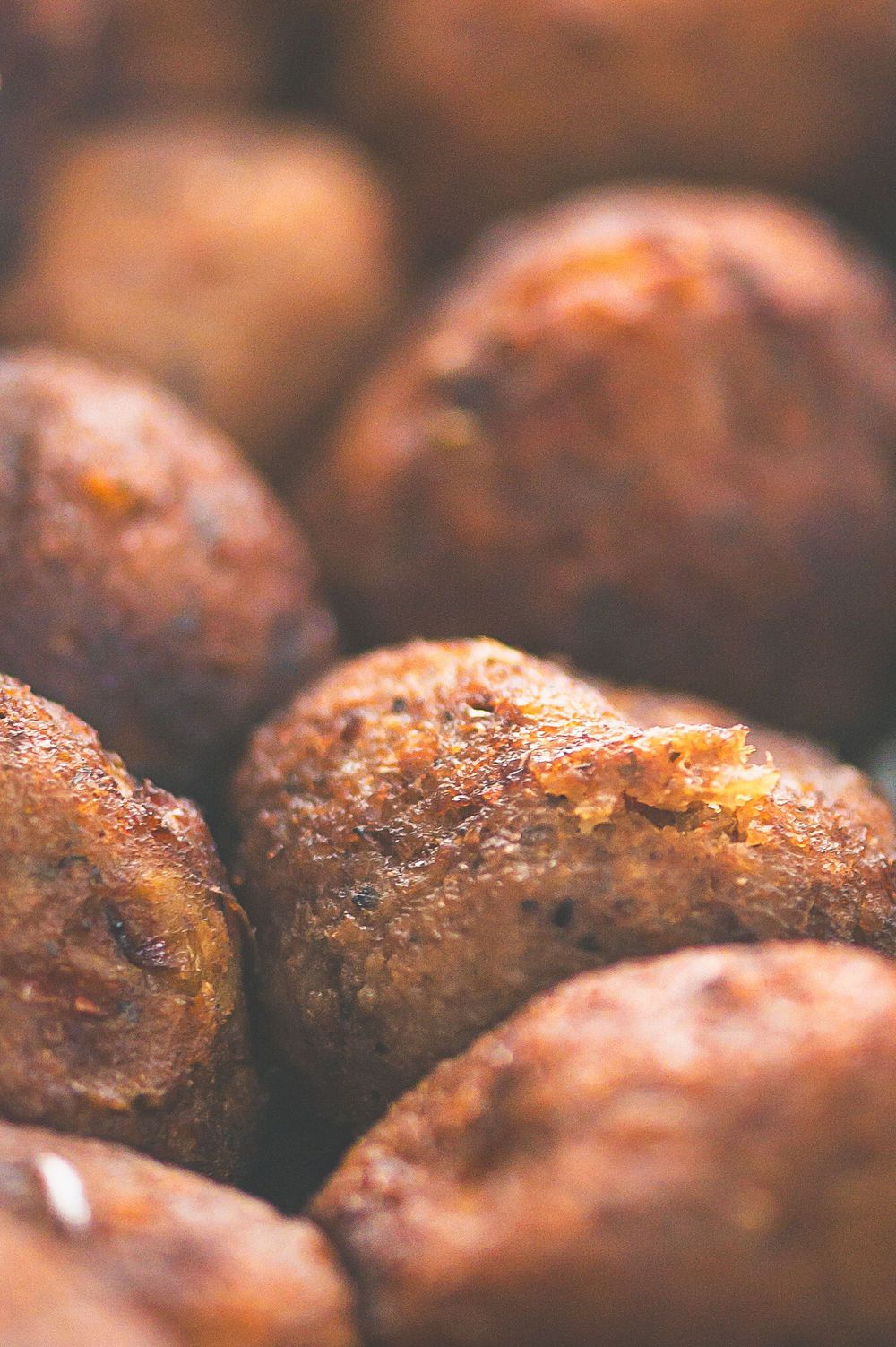 Close-up macro shot of roasted meatballs with crispy browned exterior showing rich texture and caramelization.