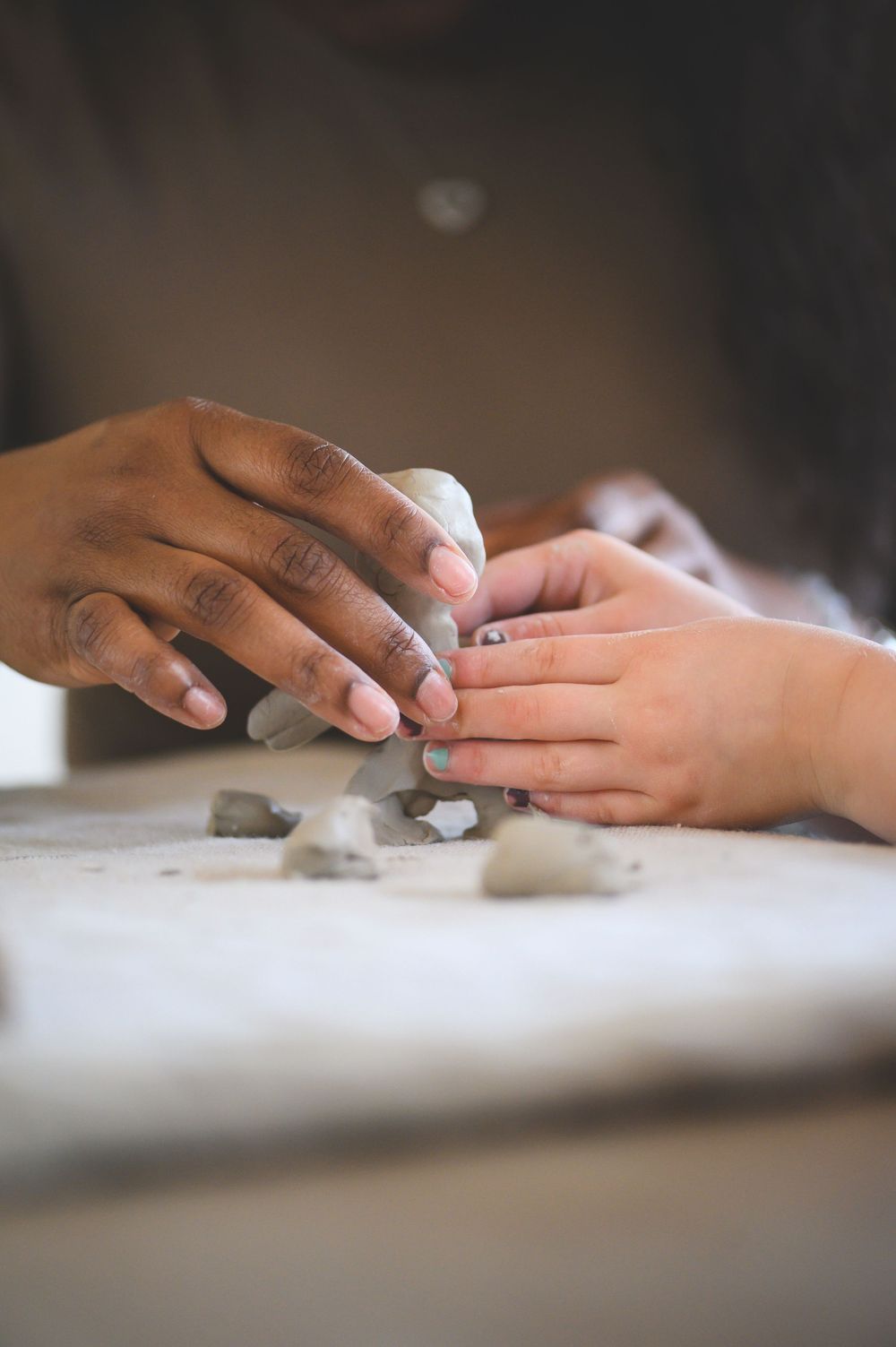 Hands working with clay or dough on a light colored surface.