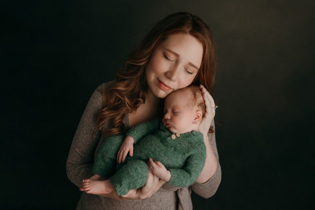 A series of intimate photos showing tender moments between a parent and infant in dark, moody lighting taken at the studio in victoria bc