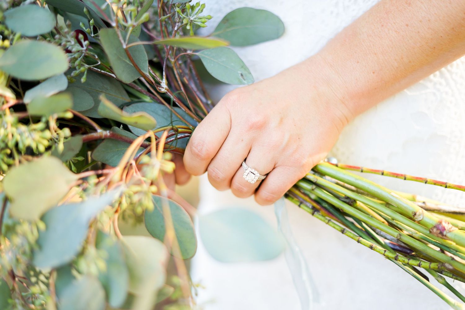 Close-up of a hand holding a wedding bouquet with eucalyptus leaves.