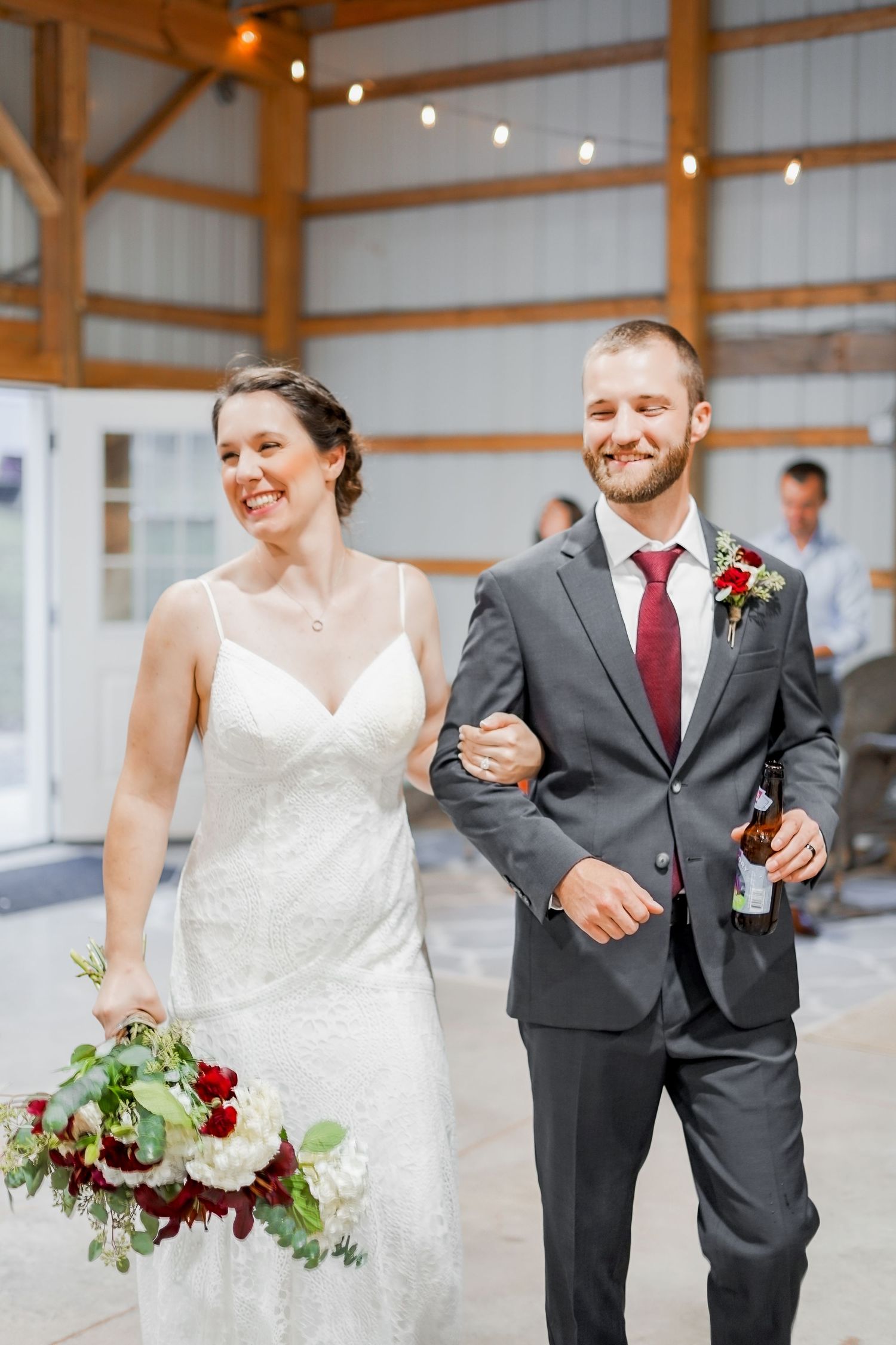 A couple celebrates in a rustic barn venue decorated with string lights.
