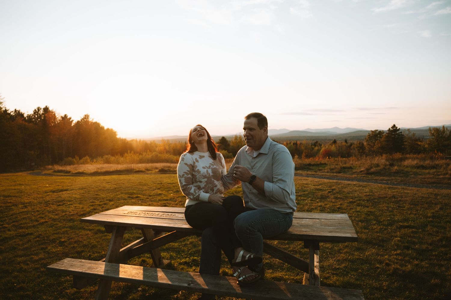A couple enjoying a romantic picnic in a field during golden hour.