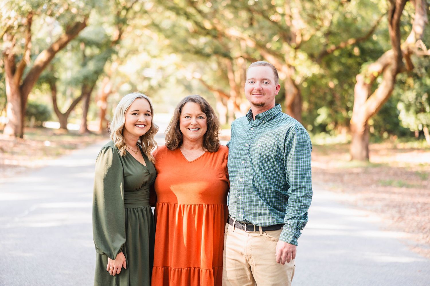 Family group photo with coordinated green and orange outfits on outdoor path.