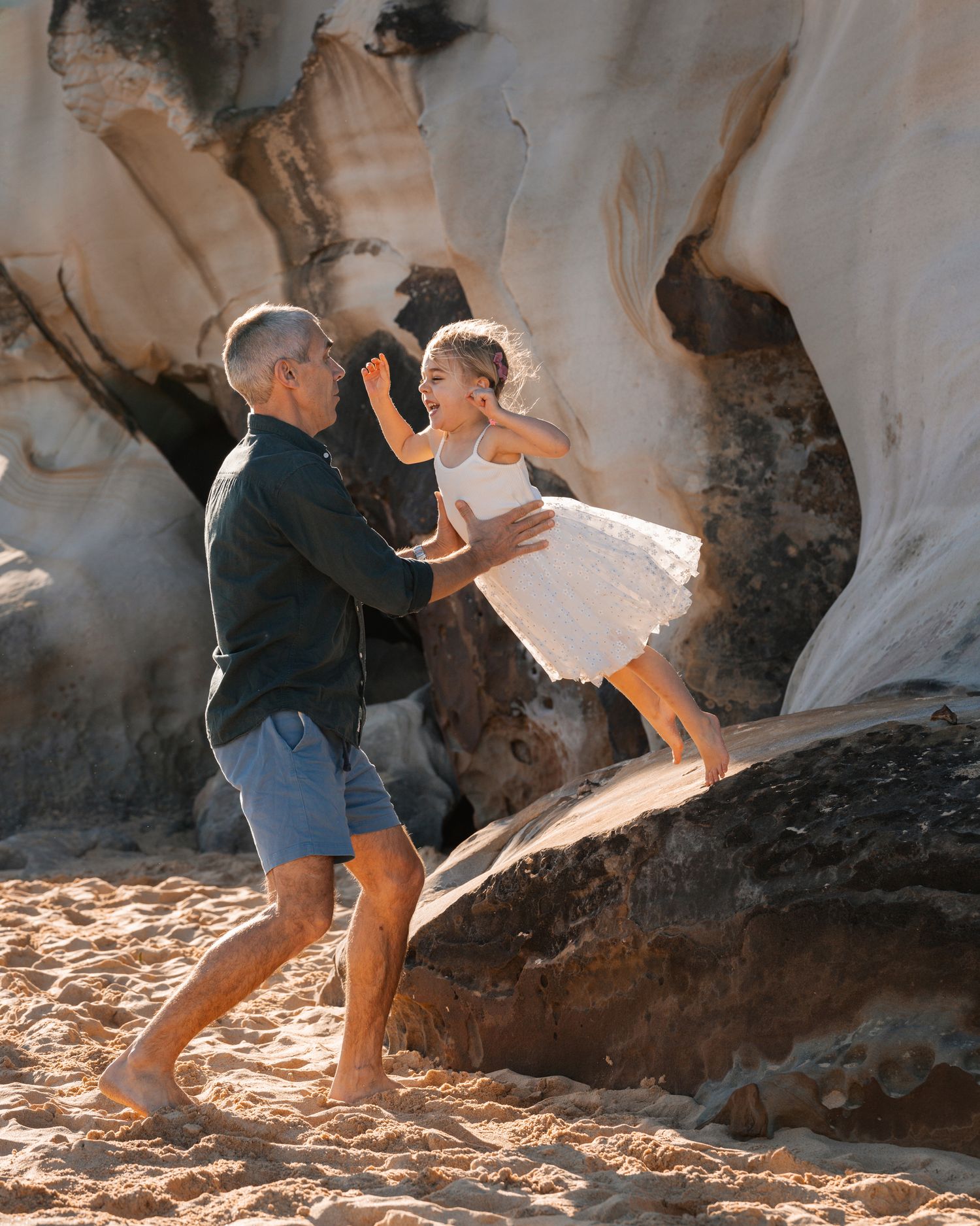 northern beaches family photoshoot dad catches daughter when she happily jumps from a rock