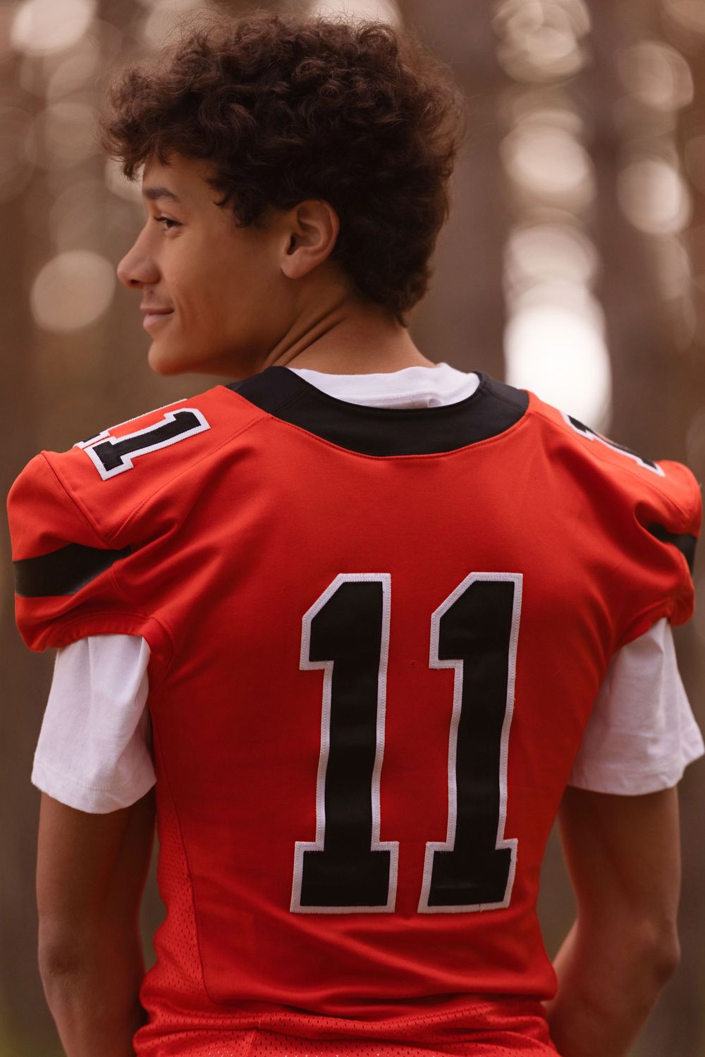 Four athletes wearing red and white sports jerseys with number 11 shown from behind in a row.