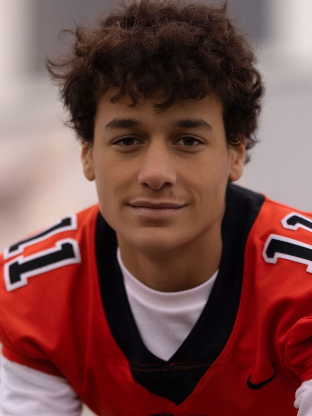 A student athlete in a red and black sports uniform poses for a series of close-up headshots.