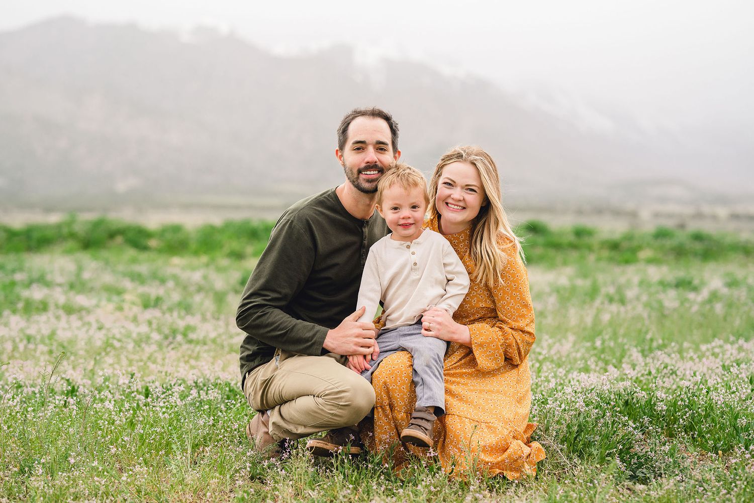 family of three in a green field