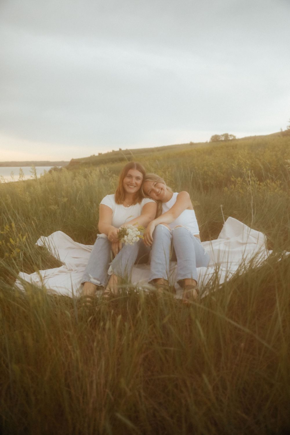 Two people relaxing in tall grass during golden hour.
