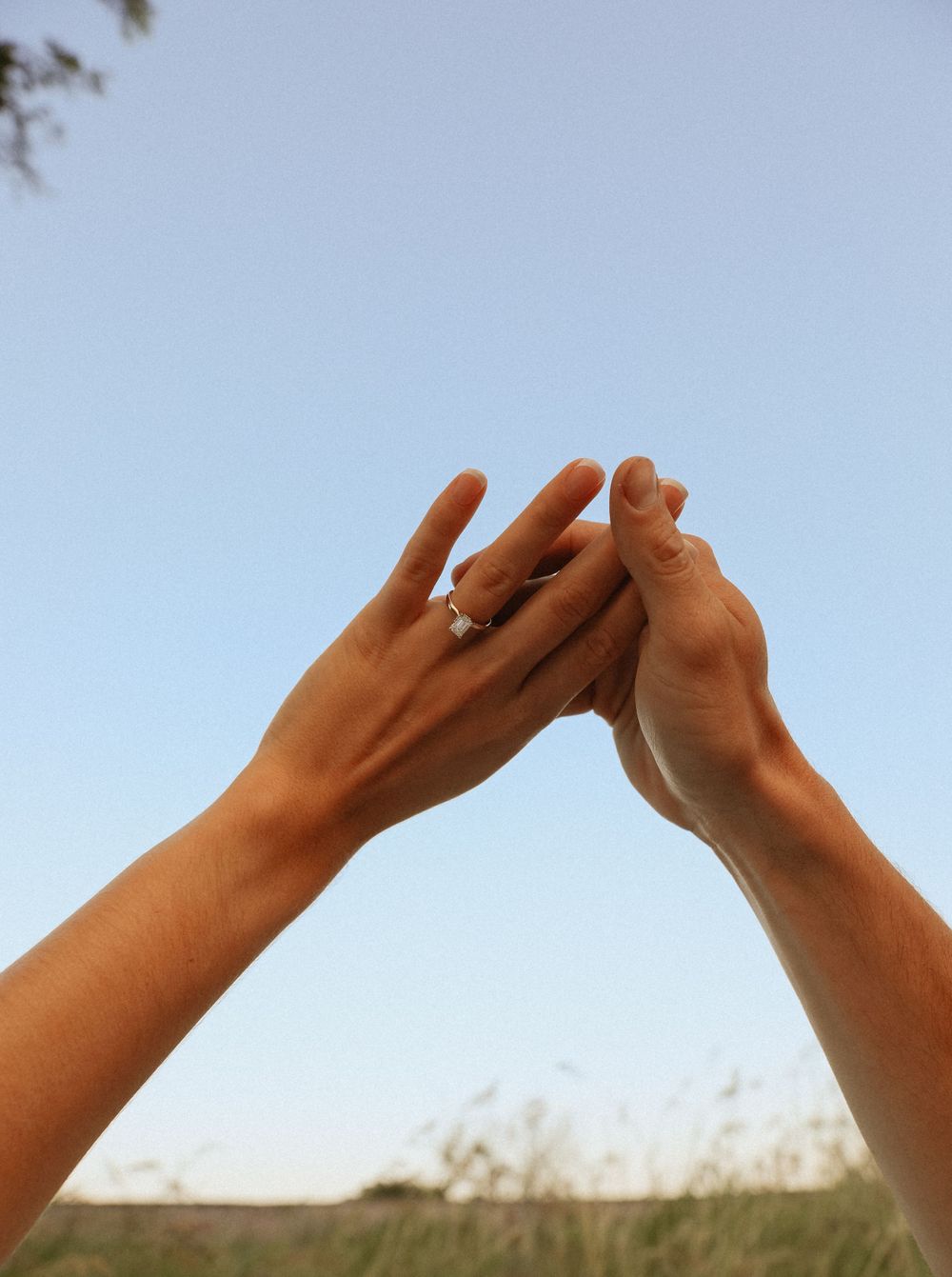 Silhouetted hands making heart shape against blue sky background.