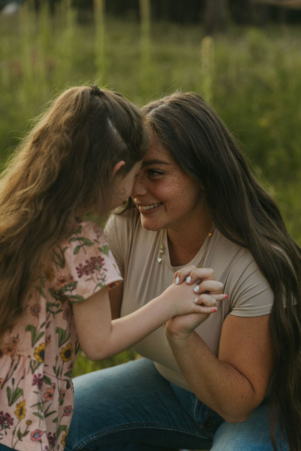 Tender moment between parent and child sharing laughter in summer field.