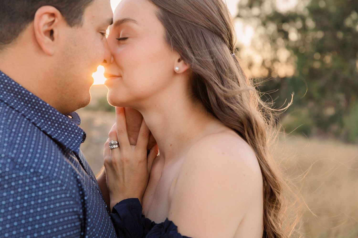 Romantic couple sharing an intimate moment against a soft natural background.