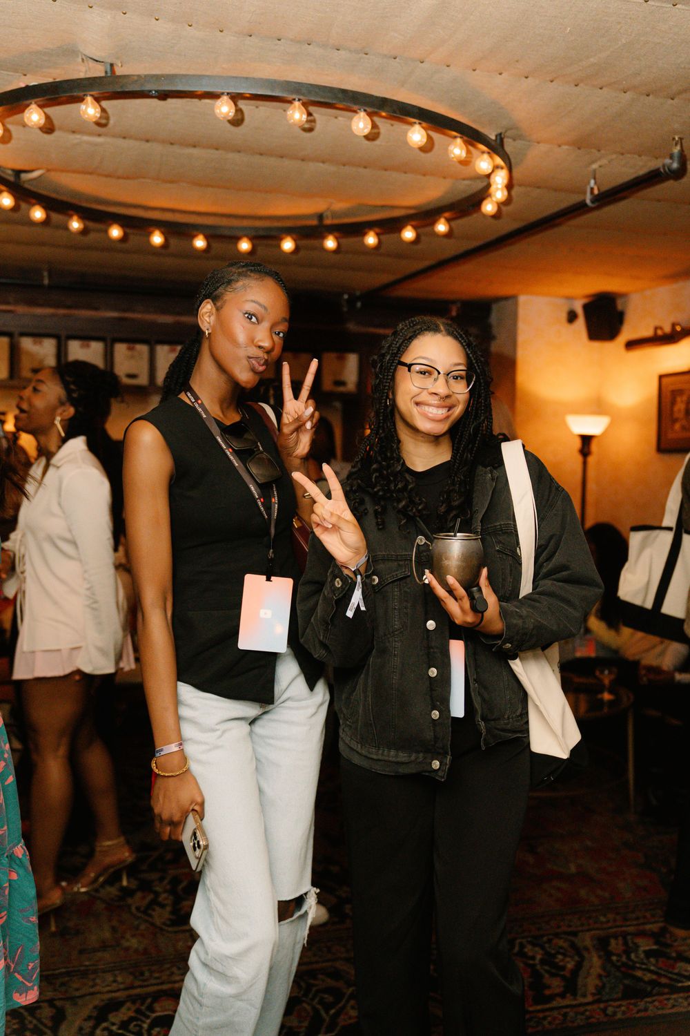 Event attendees pose together under circular pendant lighting at an indoor venue.