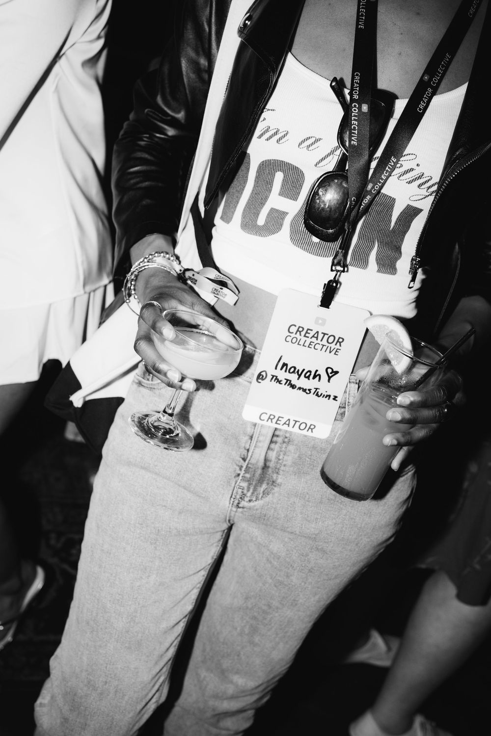 Black and white photo showing hands holding a cocktail glass and wearing light jeans with an ICON logo visible.