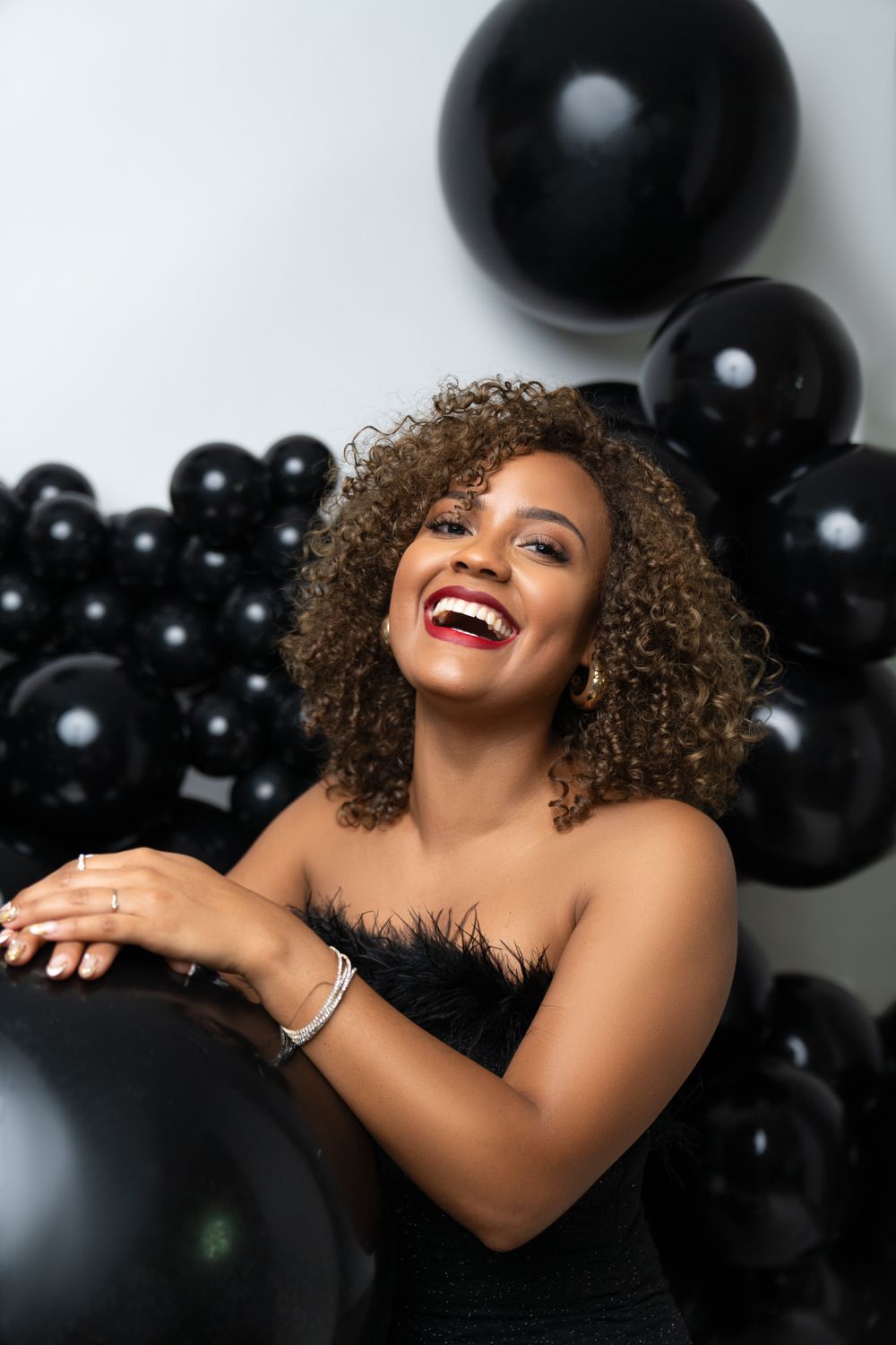 Festive portrait with black balloons featuring glamorous styling and joyful expression.