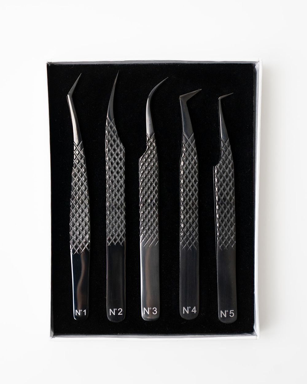 Set of five precision tweezers arranged in black display case.