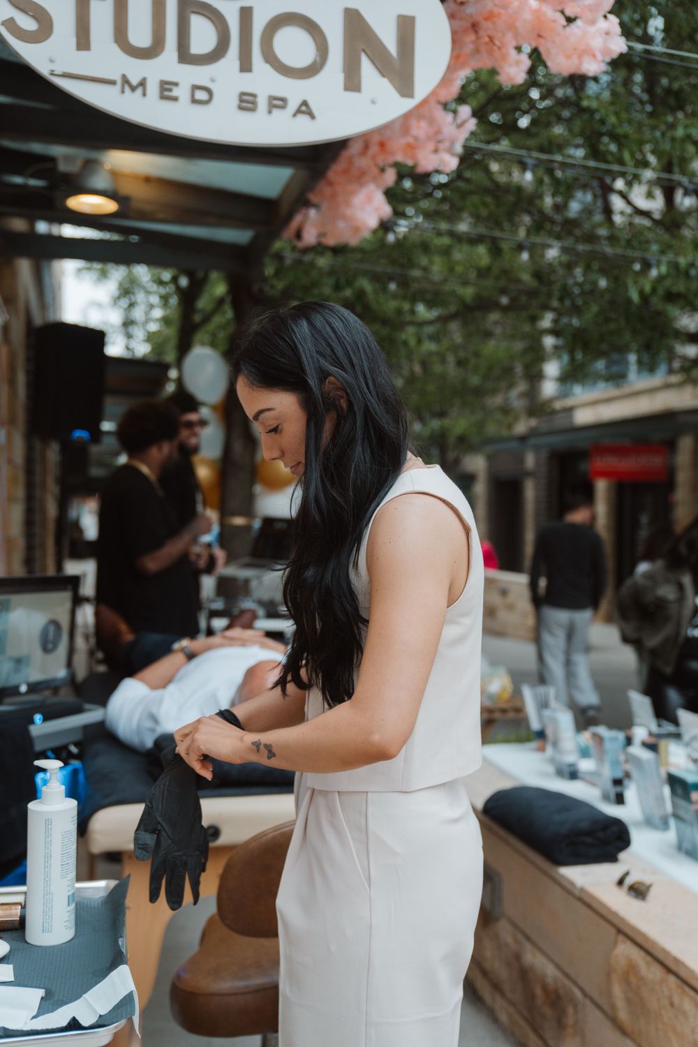 A professional at Studion Med Spa prepares beauty treatment supplies at an outdoor station.