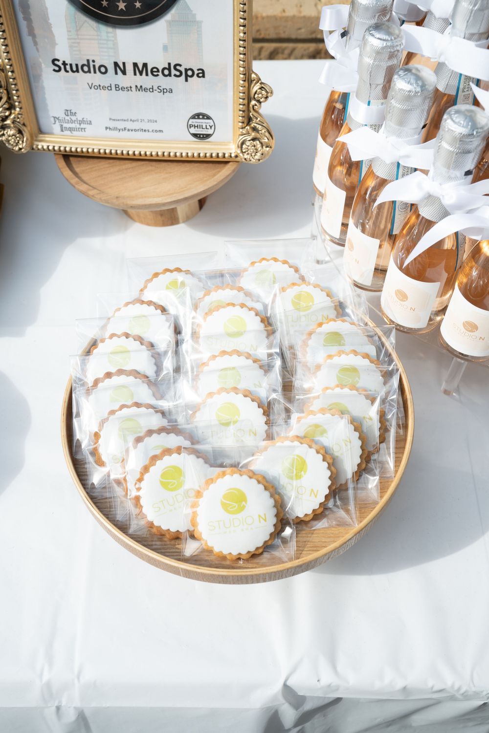 Decorated sugar cookies with lemon design displayed on wooden plate next to Studio N MedSpa signage and glass bottles.