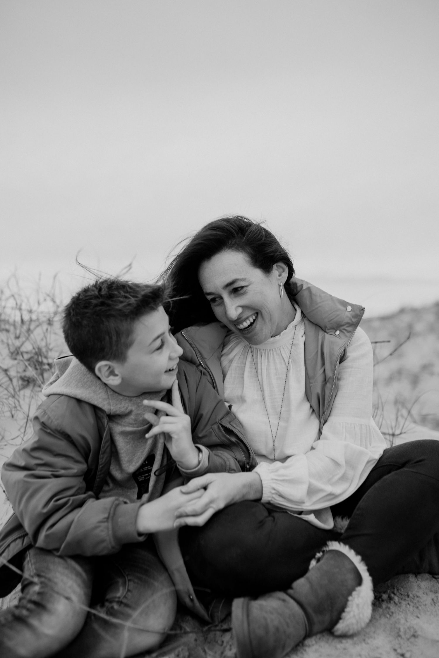 A heartwarming black and white photograph of shared laughter on the dunes.
