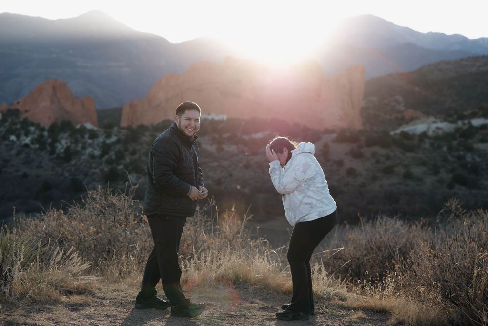 Couple embraces in a scenic mountain landscape during golden hour sunset.