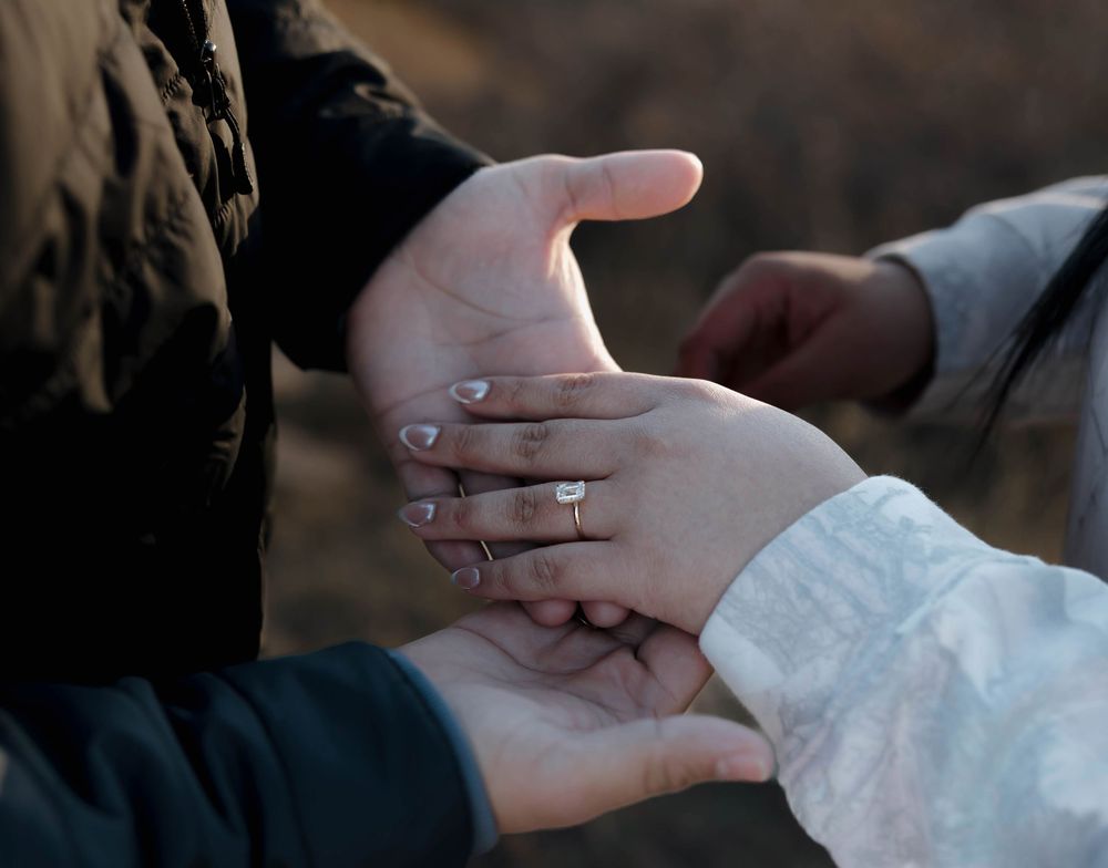 Close-up sequence of hands exchanging wedding rings during an intimate outdoor ceremony.