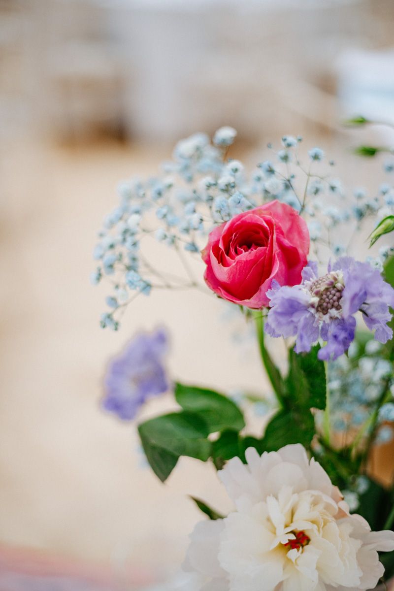 Close-up of a vibrant floral arrangement featuring a pink rose, purple flowers, and baby's breath.