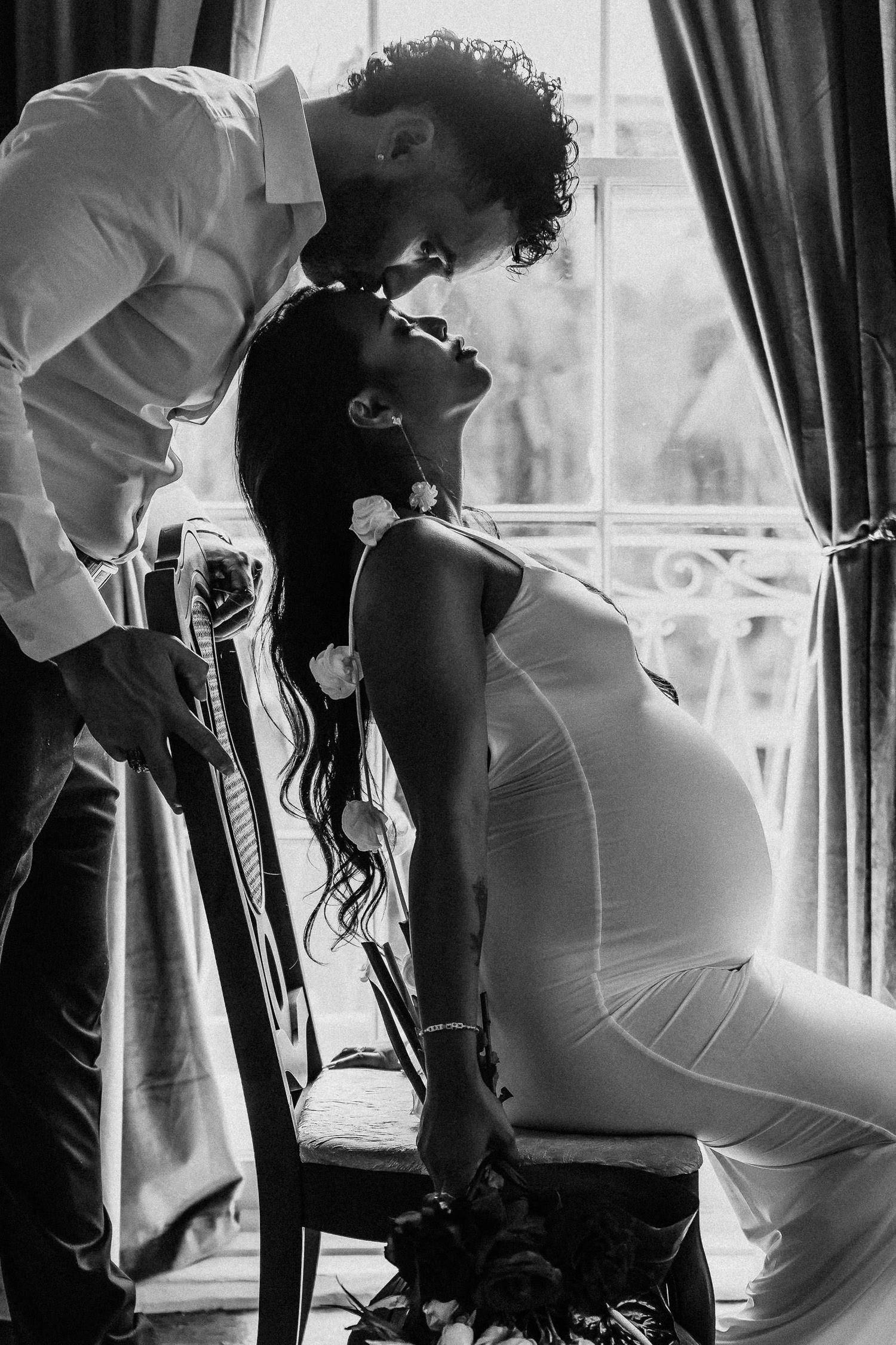 A romantic black and white photo series showing a couple in silhouette by a window. pregnant boudoir photography.