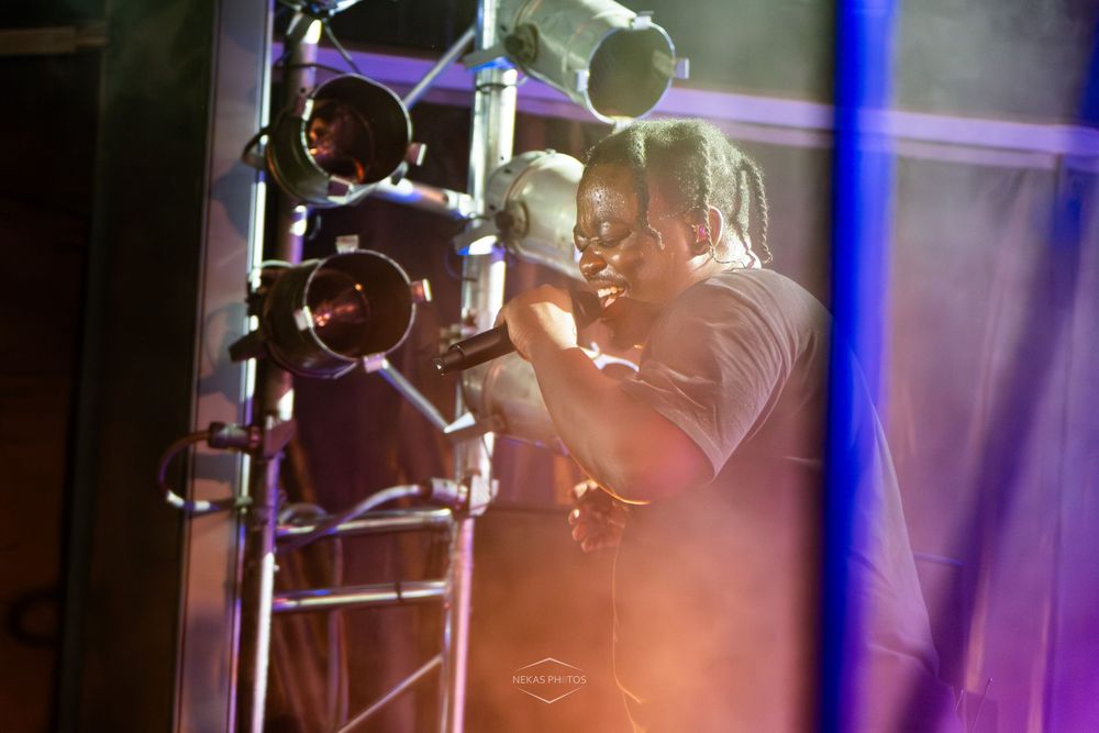 Cameraman operating a professional film camera on a metal rig under dramatic stage lighting at a live event.