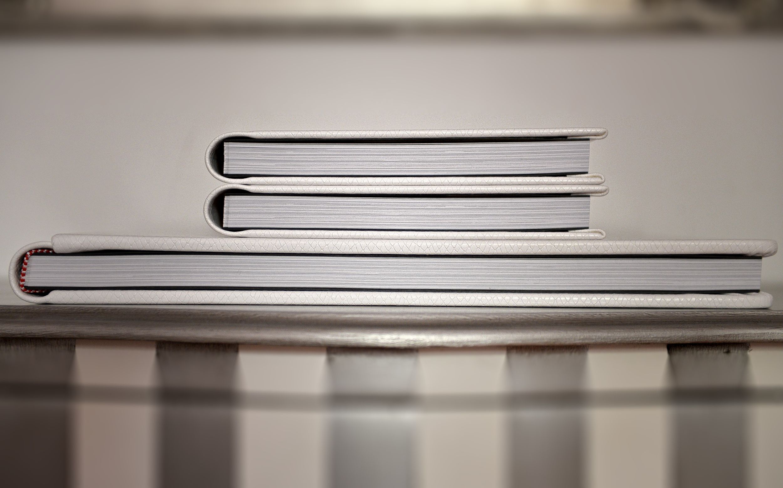Minimalist black and white macro shot of book spines stacked on a reflective surface with shallow depth of field.