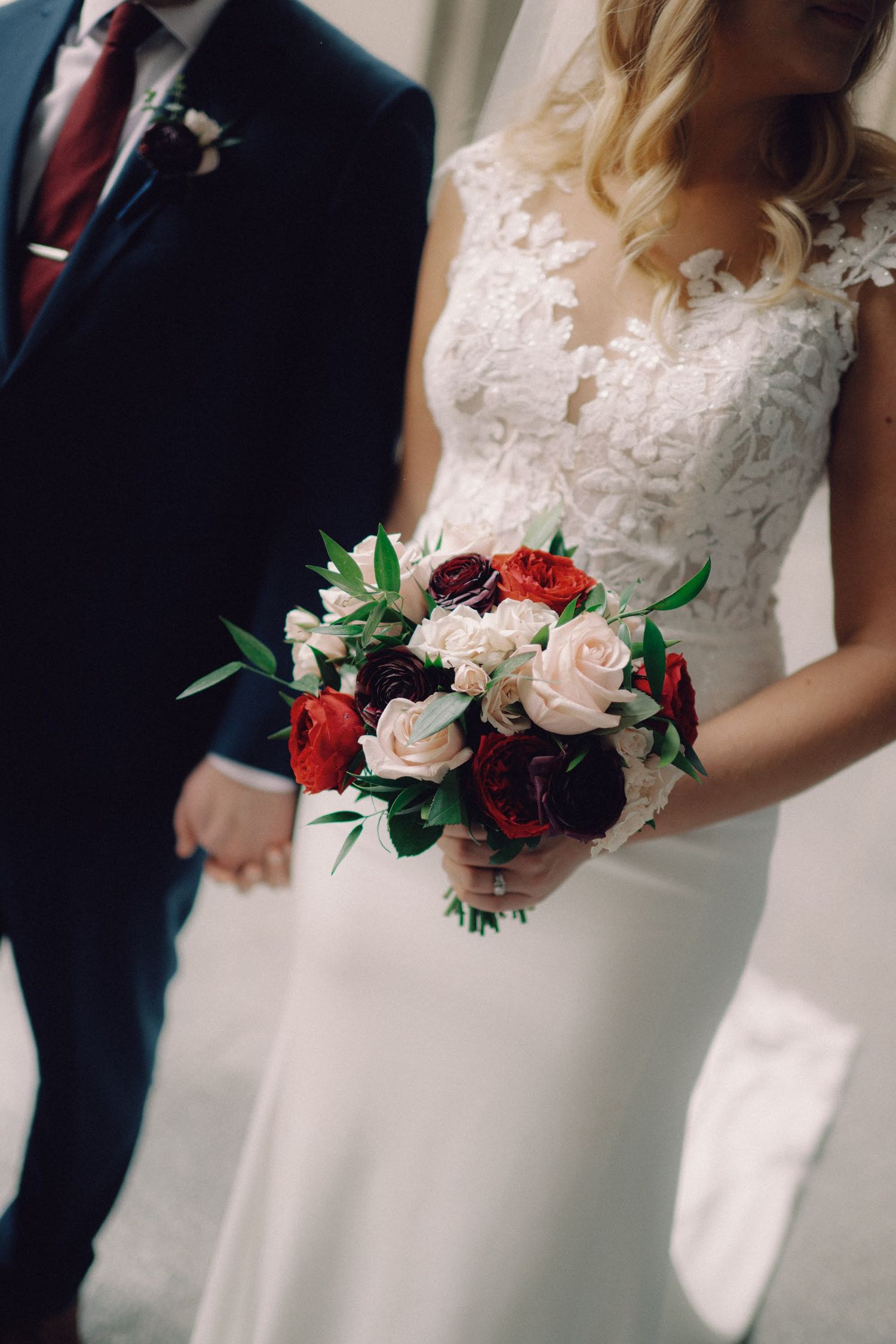 Rustic wildflower bouquet with white cosmos, burgundy dahlias, and orange blooms resting on a weathered wooden fence.